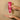 Moroccanoil Dahlia Rouge Hand Cream in a pink tube held above an open palm containing cream.